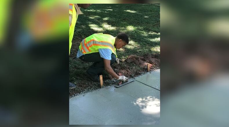 An employee in last year's summer youth employment program helps repair a sidewalk.