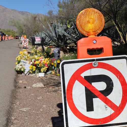 "No parking" signs stand along one side of the road that Nancy Guthrie lives on in Tucson, Ariz., Sunday, Feb. 22, 2026, while canopies and vehicles of people covering the investigation line the other side. (AP Photo/Felicia Fonseca)