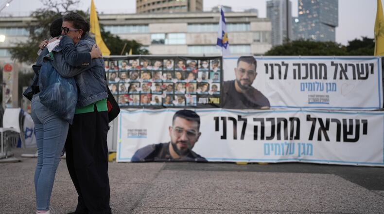 Two women embrace next to a banner with a photo of Ran Gvili after the announcement that the hostage, whose remains were the last to be recovered from Gaza, had been identified, in a plaza known as Hostages Square in Tel Aviv, Israel, Monday, Jan. 26, 2026. (AP Photo/Oded Balilty)