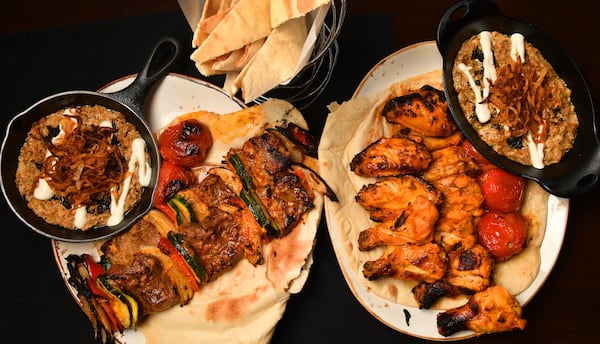 Kashk Bademjoon (eggplant spread with crispy mint and fried onions), Beef Shish Kebabs, Zafron Wings, and a second dish of Kashk Bademjoon. Shown with bread in a basket at top. (Styling by Peter Teimori / Chris Hunt for the AJC) 