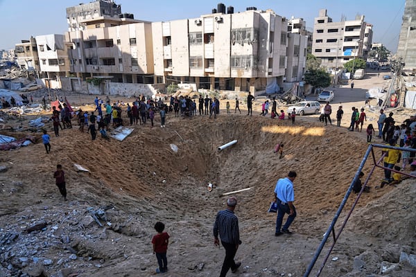 Palestinians gather around a crater caused by an Israeli strike on a displacement tent camp in Gaza City, June 28, 2025. (AP Photo/Jehad Alshrafi)