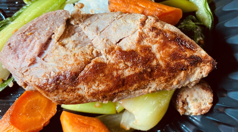 Canoe's Asian-flavored, curry-brined pork tenderloin is served with lemongrass sausage, coconut rice and tom yum. Bob Townsend for The AJC