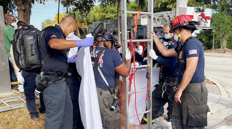 Delray Beach Fire Rescue remove a grate to access a storm drain and use a ladder and a harness to raise a trapped woman to ground level on Tuesday.