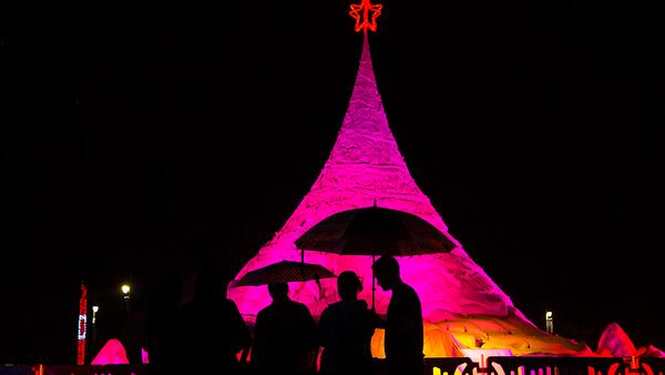 People stand under umbrellas as it rains at the 2016 tree lighting of Sandi at the West Palm Beach Waterfront. (Greg Lovett / The Palm Beach Post)