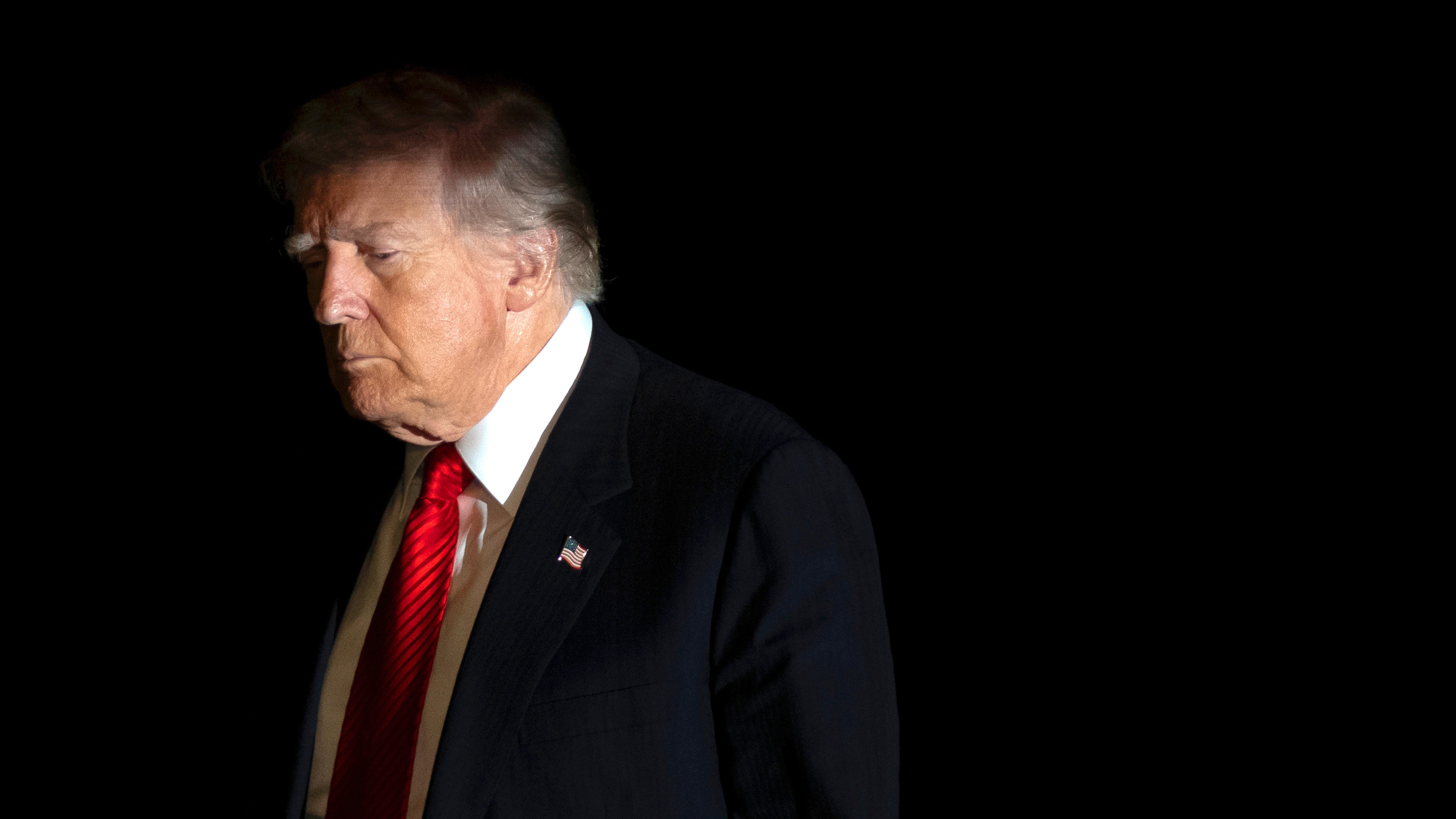 President Donald Trump is illuminated by a camera flash as he walks across the South Lawn of the White House, Sunday, Nov. 2, 2025, in Washington, after returning from a trip to Florida. (AP Photo/Mark Schiefelbein)