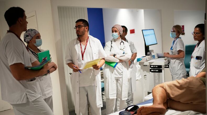 Doctors and nurses take care of a patient at the emergency department of the Paris-Saclay Hospital, outside Paris, Tuesday June 30, 2026. (AP Photo/Christophe Ena )