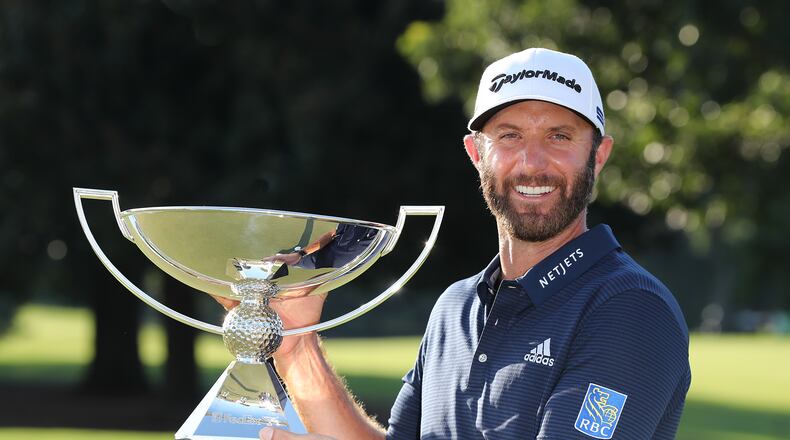 Dustin Johnson is presented the FedEx Cup trophy after sinking his birdie putt on the 18th green to win the Tour Championship and FedEx Cup by three strokes at 21-under par at East Lake Golf Club on Monday, Sept. 7, 2020 in Atlanta.   Curtis Compton / Curtis.Compton@ajc.com