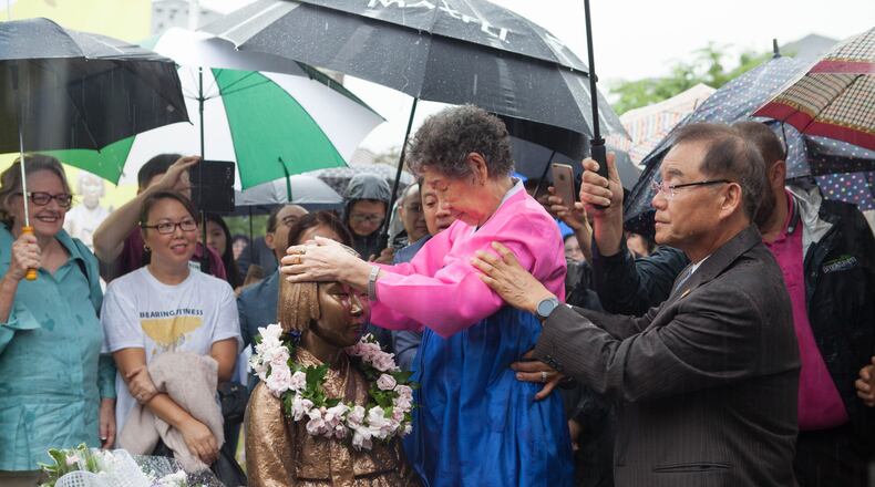 In a photo from the June 30 unveiling of the Comfort Women memorial statue in Brookhaven, Il-Chul Kang, 89, a Korean survivor of the atrocity, places her hands on the head of the bronze figure. Photo: David Kwon/The Korea Daily