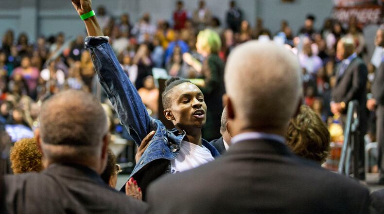 A protester is escorted out after interrupting Democratic presidential candidate Hillary Rodham Clinton, in the background, Friday, Oct. 30, 2015, during a campaign event at Clark Atlanta University in Atlanta. (AP Photo/David Goldman)