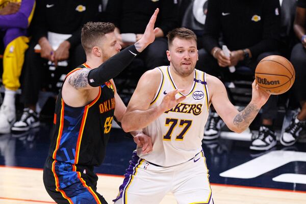 Los Angeles Lakers guard Luka Doncic (77) looks to pass the ball away from Oklahoma City Thunder center Isaiah Hartenstein, left, during the first half of an NBA basketball game Sunday, April 6, 2025, in Oklahoma City. (AP Photo/Nate Billings)