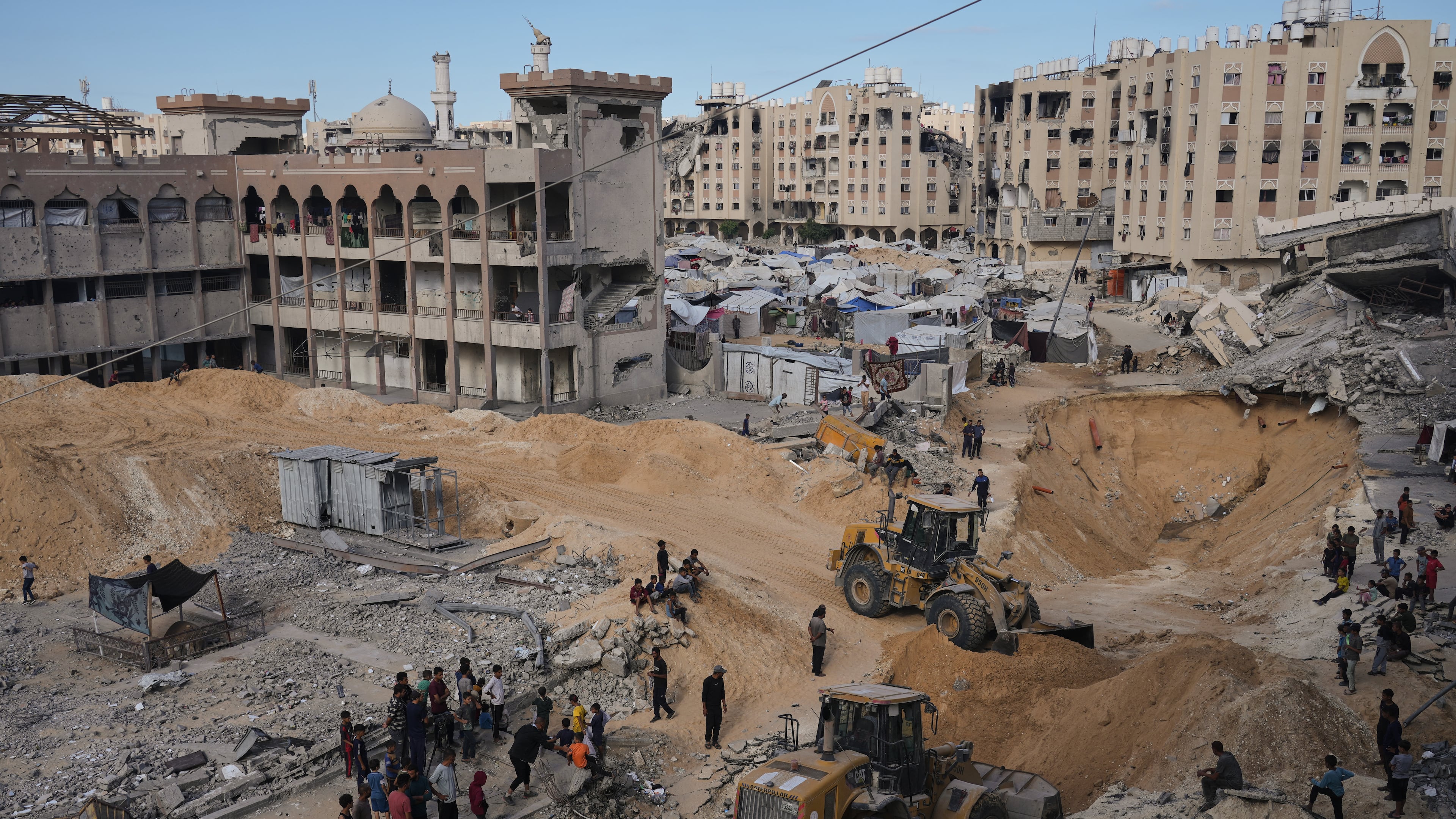 Palestinians watch members of the Hamas militant group searching for bodies of the hostages in an area in Hamad City, Khan Younis, in the southern Gaza Strip, Saturday, Oct. 18, 2025. (AP Photo/Jehad Alshrafi)