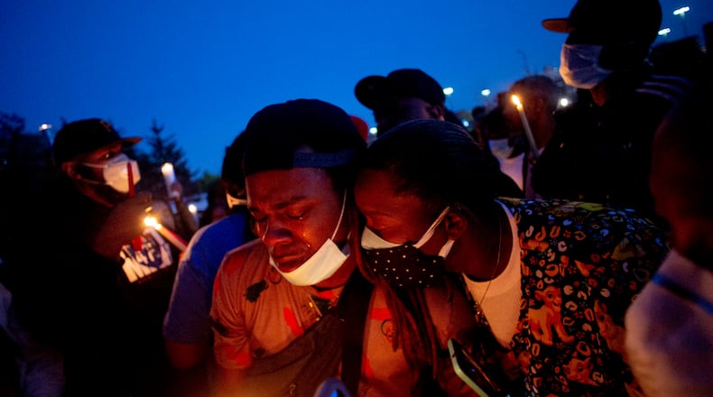 Maalik Mitchell, center left, sheds tears as he says goodbye to his father, Calvin Munerlyn, during a vigil Sunday in Flint, Michigan.  Munerlyn was shot and killed Friday at a Family Dollar store in Flint. He'd worked at the store as a security guard for a little more than a year.