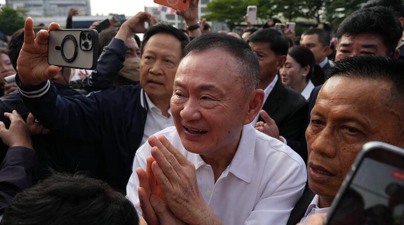 Former Thailand Prime Minister Thaksin Shinawatra, center, gestures to his supporters following his release on parole from a Bangkok prison in Bangkok, Thailand, Monday, May 11, 2026. (AP Photo/Sakchai Lalit)