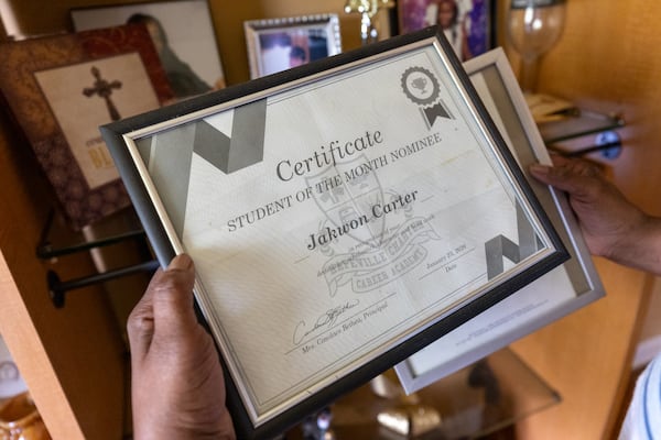 Linda Sinkfield holds a student achievement award for her grandson Jakwon Carter at her home in College Park. Jakwon was known for his intelligence — and video game skills. (Arvin Temkar/AJC)