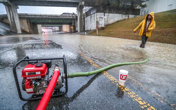 Michael Navarro adjusts a pump on Chamblee Dunwoody Road, which is flooded. The road is closed between American Industrial Way and New Peachtree Road