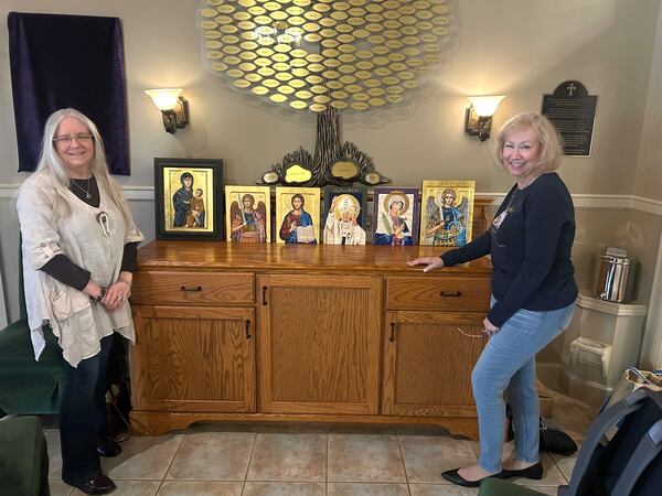 Iconographers Karen Webster and Teresa Satola pose next to a collection of their icons inside Our Lady of the Mountains Catholic Church in Jasper. (Olivia Wakim/AJC)