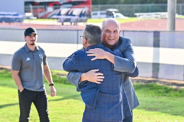 Georgia Southern University President Kyle Marrero hugs football coach Clay Helton during the Eagle Walk on Oct. 9 in Statesboro. (Sarah Peacock for the AJC)