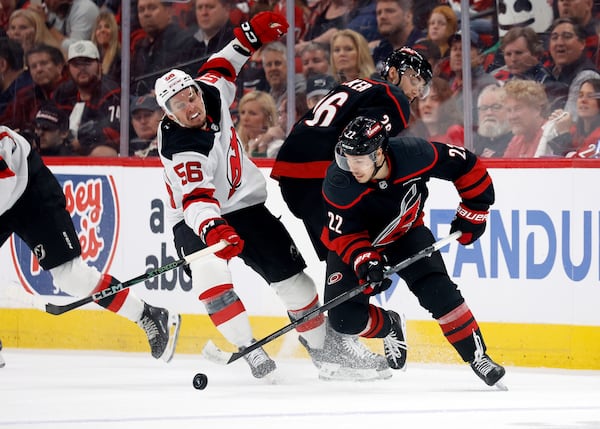 Carolina Hurricanes' Logan Stankoven (22) gathers in the puck around teammate Sean Walker (26) and in front of New Jersey Devils' Erik Haula (56) during the third period of Game 5 of an NHL hockey Stanley Cup first-round playoff series in Raleigh, N.C., Tuesday, April 29, 2025. (AP Photo/Karl DeBlaker)