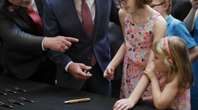 After the signing a bill to allow the in-state cultivation and manufacture of a marijuana oil for medical purposes, Gov. Brian Kemp, with the bill’s author, state Rep. Micah Gravley, R-Douglasville, gave a ceremonial pen to 13-year-old Alaina Cloud. Alaina, who has a severe form of epilepsy that causes uncontrollable seizures, was joined by her sister, Courtney, 5. Kemp, joined by medical marijuana users and advocates, signed HB 324, which will also allow medical marijuana oil to be sold in Georgia for the first time. Bob Andres / bandres@ajc.com