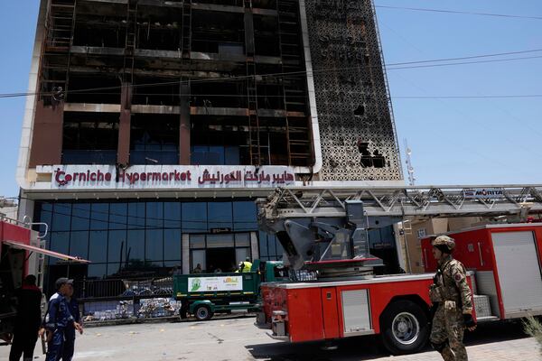 Firefighters gather in front of a burning hypermarket building in Kut, Iraq, Thursday, July 17, 2025. (AP Photo/ Hadi Mizban)