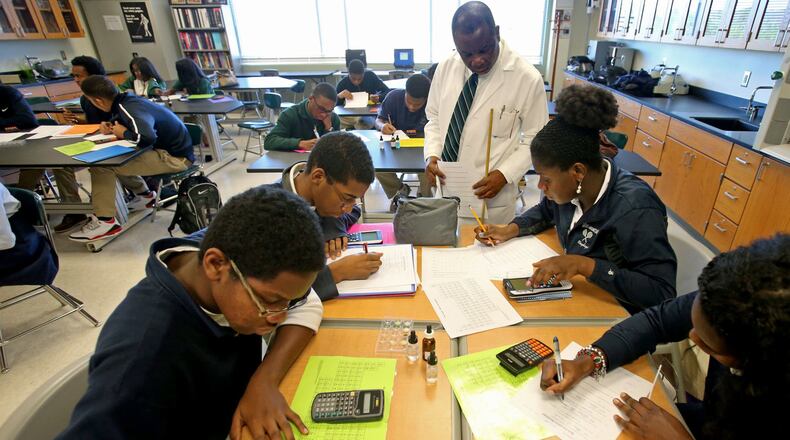 Chemistry teacher Fred Okoh, top center, looks over the work of sophomore students in his classroom at Arabia Mountain High School in this AJC file photo. Once again, Arabia Mountain High has one of the highest four-year graduation rates in DeKalb County.
