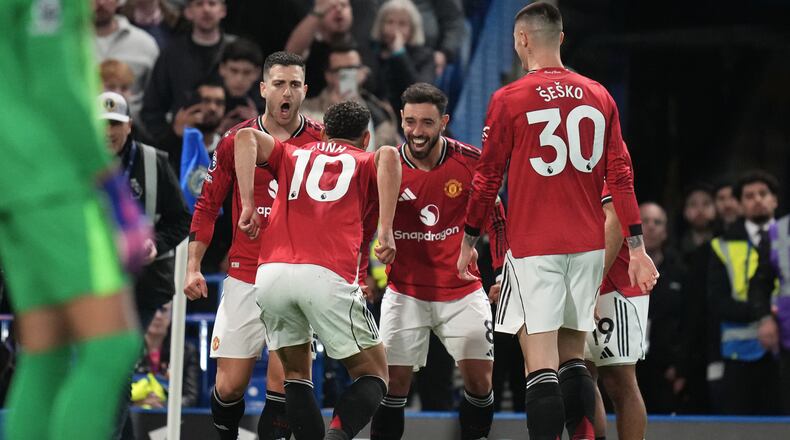 Manchester United's Matheus Cunha celebrates with teammates after scoring the opening goal during the English Premier League soccer match between Chelsea and Manchester United in London, Saturday, April 18, 2026. (AP Photo/Kirsty Wigglesworth)