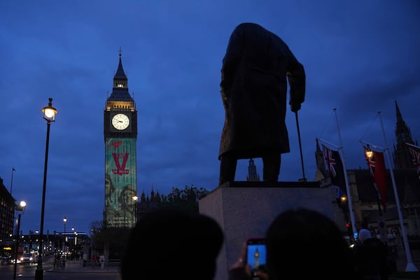 Images are projected onto the Queen Elizabeth Tower, in the Houses of Parliament, including the British World War II Prime Minister Winston Churchill, whose statue is in the foreground, during the V-E Day 80th anniversary events in London, Tuesday, May 6, 2025. (AP Photo/Alastair Grant)