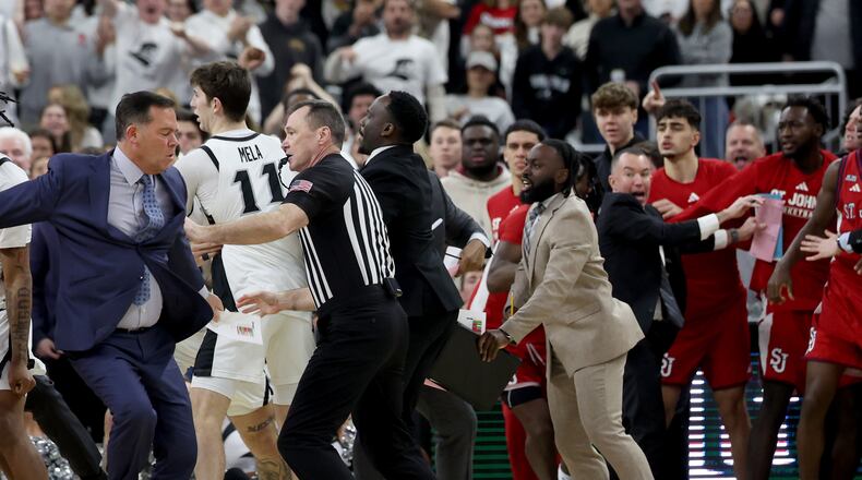 A game official separates St. John's coaches and players after a fight broke out during the second half of an NCAA college basketball game against Providence, Saturday, Feb. 14, 2026, in Providence, R.I. (AP Photo/Mark Stockwell)