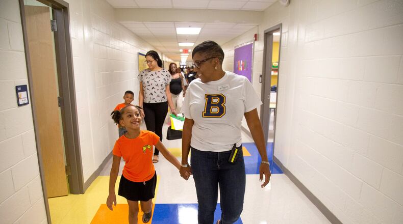 Beecher Hills Elementary school principal Crystal Jones (R) walks down the hall while holding the hand of Olivia Sorel during the first open house after the schools’ extensive renovation Friday, August 9, 2019.STEVE SCHAEFER / SPECIAL TO THE AJC