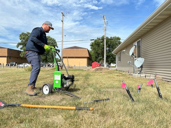 Joshua Herman pumps carbon monoxide into burrows dug by Richardson's ground squirrels along an apartment building on Monday, July 14, 2025, in Minot, N.D. (AP Photo/Jack Dura)