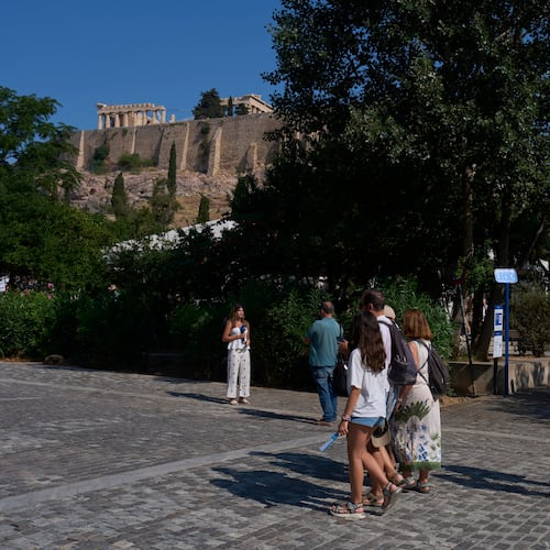 Tourists walk near the Acropolis in Athens, Greece, Tuesday, July 21, 2026, after two tourists were stabbed and injured nearby in an attack on a pedestrian street near the entrance to the archaeological site. (AP Photo/Petros Giannakouris)