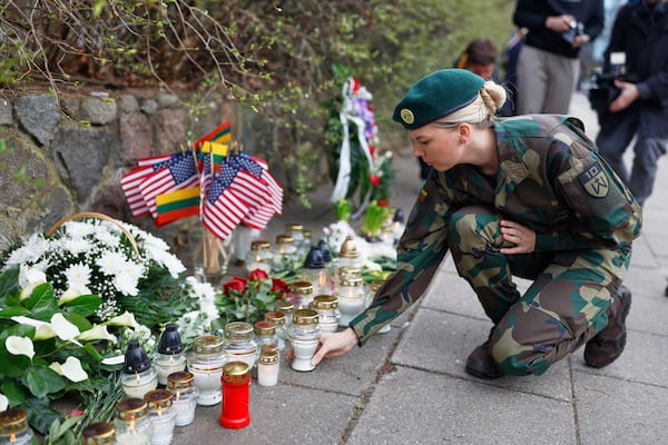 A Lithuanian Army soldier lights a candle in memory of three soldiers found dead on Monday at a training range in Pabrade, near the U.S. Embassy in Vilnius, Lithuania, Tuesday, April 1, 2025. (AP Photo/Mindaugas Kulbis)