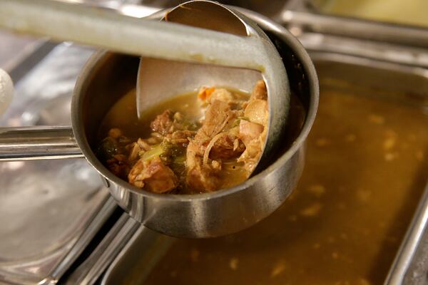 FILE - Sous chef Darren Chabert serves up chicken and andouille gumbo at Emeril's Delmonico in New Orleans, Monday, Feb. 17, 2014. (AP Photo/Gerald Herbert, File)