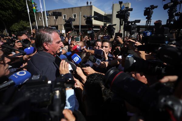 Brazil's former President Jair Bolsonaro is surrounded by the press as he leaves the Secretariat of Penitentiary Administration where he arrived after the Supreme Court ordered him to be fitted with an electronic ankle monitor in Brasilia, Brazil, Friday, July 18, 2025. (AP Photo/Luis Nova)