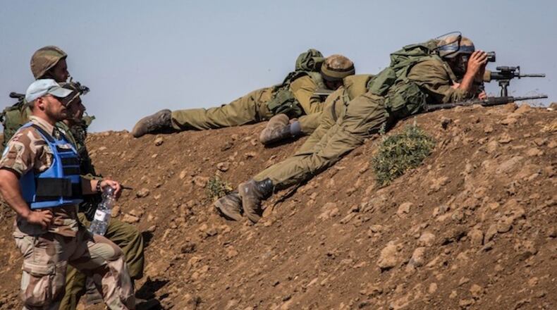 A Norwegian member of the United Nations Disengagement Observer Force stands by Israeli soldiers keeping position in the Israeli-occupied Golan Heights on Sept. 11, 2014. (Xinhua/Sipa USA/TNS)