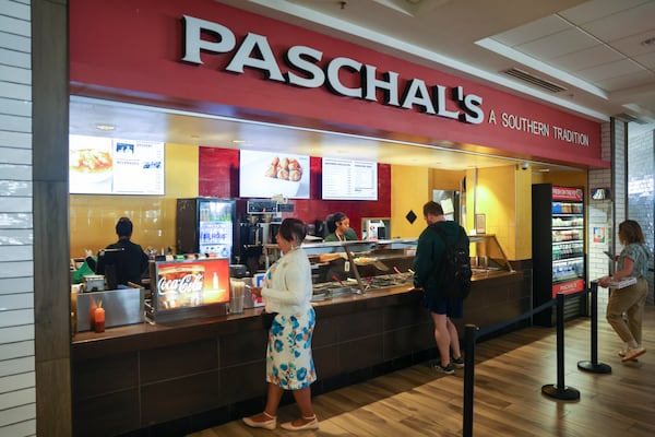 The exterior of Paschal's buffet-style restaurant is shown with two customers at the counter and one person working behind the counter.