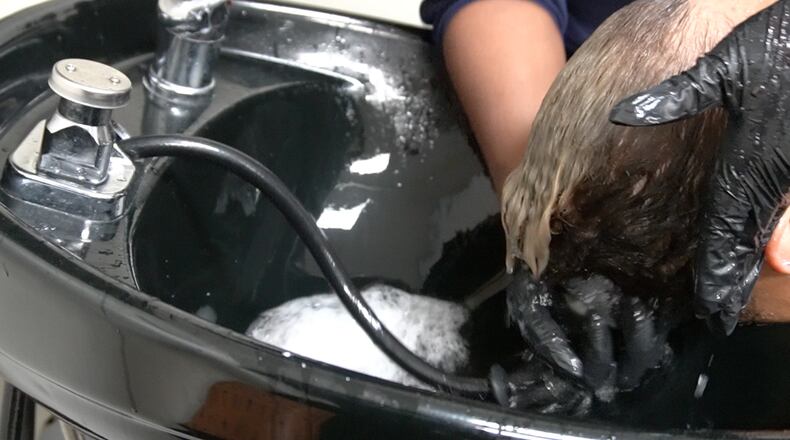 A beautician washes a relaxer out of a client’s hair at a salon in Atlanta. Social and economic pressures have long compelled Black girls and women to straighten their hair. But mounting evidence suggests chemical hair straighteners could be a health hazard. (Kara Nelson/KFF Health News)