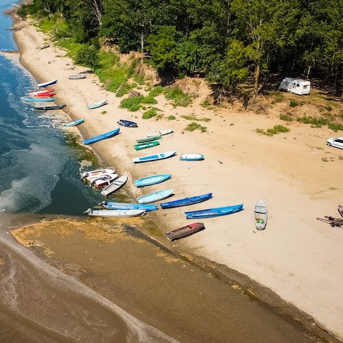 People stand on a bank of sand on the Danube River as usually submerged areas are exposed due to extreme low levels of the water following an extended period of drought in Corabia, Romania, Wednesday, July 29, 2026. (AP Photo/Nicolae Dumitrache)