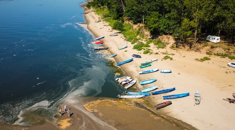 People stand on a bank of sand on the Danube River as usually submerged areas are exposed due to extreme low levels of the water following an extended period of drought in Corabia, Romania, Wednesday, July 29, 2026. (AP Photo/Nicolae Dumitrache)