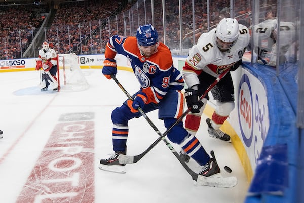 Florida Panthers' Aaron Ekblad (5) and Edmonton Oilers' Connor McDavid (97) battle for the puck during the first overtime period in Game 1 of the NHL hockey Stanley Cup final series in Edmonton, Alberta, Wednesday, June 4, 2025. (Jason Franson/The Canadian Press via AP)