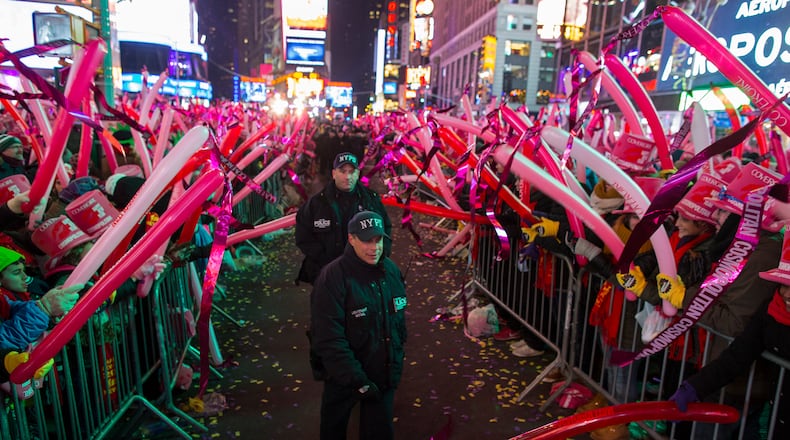 New York City police officers walk past revelers as they wait in Times Square for the stroke of midnight during New Year's Eve festivities in New York, Wednesday, Dec. 31, 2014. (AP Photo/Craig Ruttle)