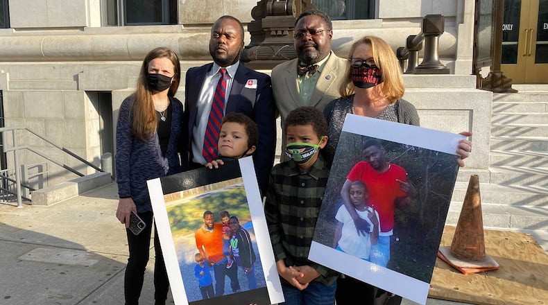 Family members of the late Antonio May and their lawyers stand on the steps of the Fulton County Courthouse in Atlanta on Nov. 16, 2021 following the indictment of six deputy sheriffs. In the foreground are two of May's three sons holding family photos. Top row from left, Shonna Rickerson, the boys' mother; attorneys Michael Harper and Teddy Reese; and April Myrick, legal guardian of both boys.