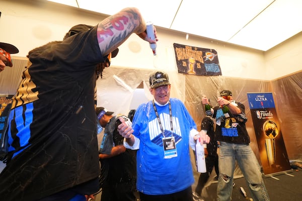 Clay Bennett, center, chairman the ownership group of the Oklahoma City Thunder, celebrates with players in the locker room after winning the NBA basketball championship with a Game 7 victory against the Indiana Pacers Sunday, June 22, 2025, in Oklahoma City. (AP Photo/Julio Cortez)