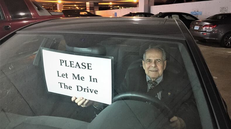 Sam Massell of the Buckhead Coalition shows a sign offered to residents to aid in getting in and out of driveways. CONTRIBUTED