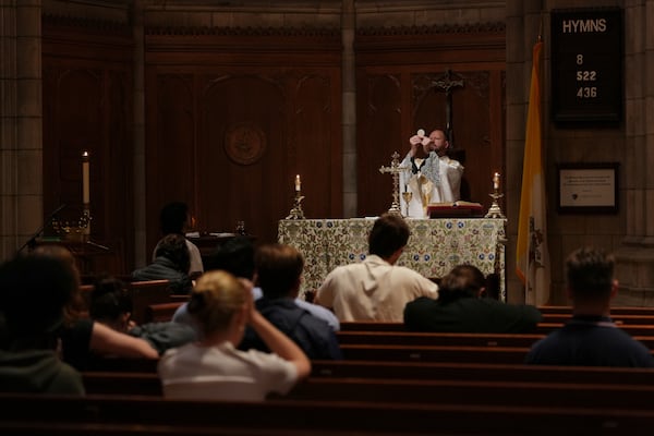 The Rev. Zachary Swantek, Princeton University’s Catholic chaplain and director of the Aquinas Institute - the university’s Catholic campus ministry - raises the host during the Eucharist at a side altar of the school's chapel during a Mass in Princeton, N.J., on Thursday, May 15, 2025. (AP Photo/Luis Andres Henao)