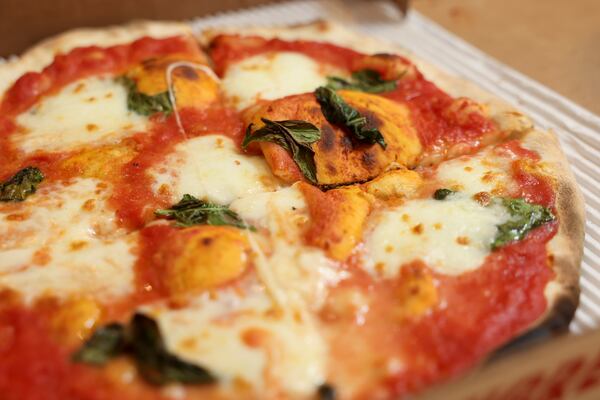 A close-up photo of a cheese and tomato-slice pizza from Varasano's Pizzeria.