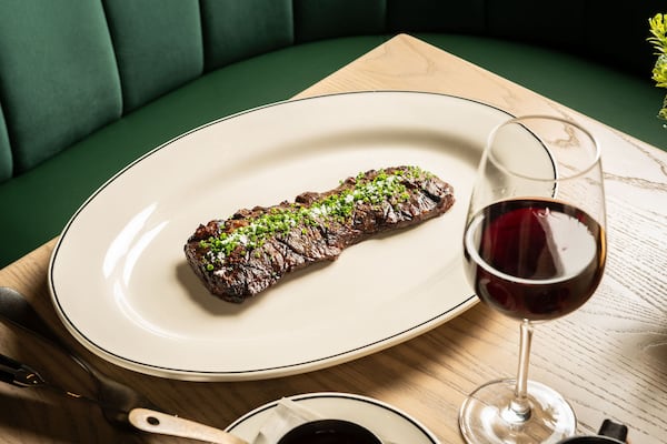 A small steak on a plate topped with a drizzle of green sauce