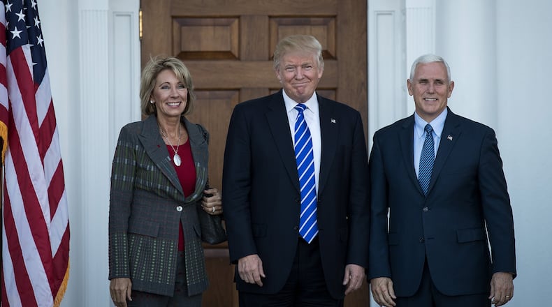 (L to R) Betsy DeVos, president-elect Donald Trump and vice president-elect Mike Pence pose for a photo outside the clubhouse at Trump International Golf Club, November 19, 2016 in Bedminster Township, New Jersey.
