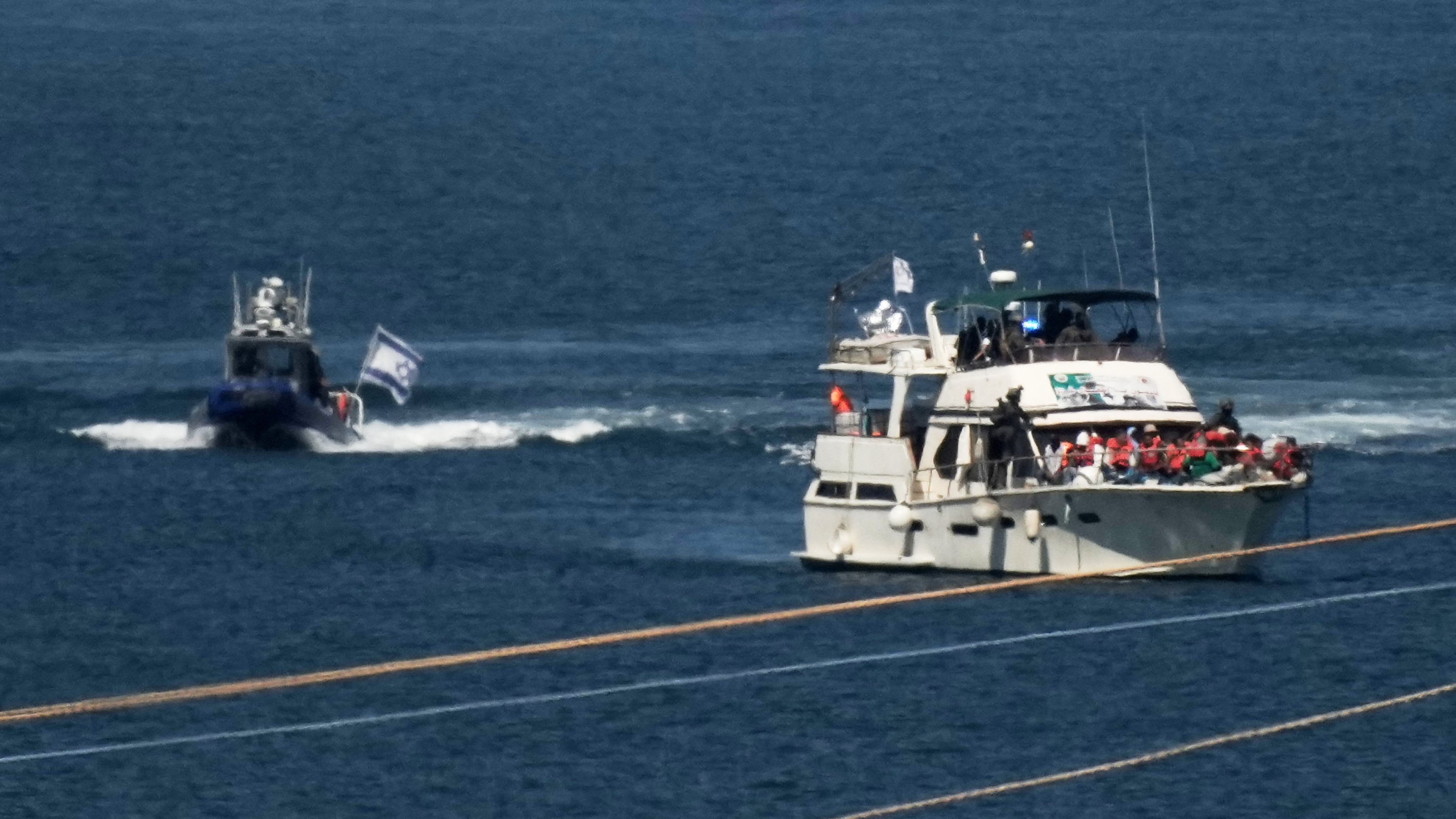 Activists in orange life jackets sit aboard a Gaza-bound Sumud flotilla boat as Israeli navy soldiers sail it into the port of Ashdod, Israel, Thursday, Oct. 2, 2025, after it was intercepted while approaching the Gaza coast. (AP Photo/Leo Correa)