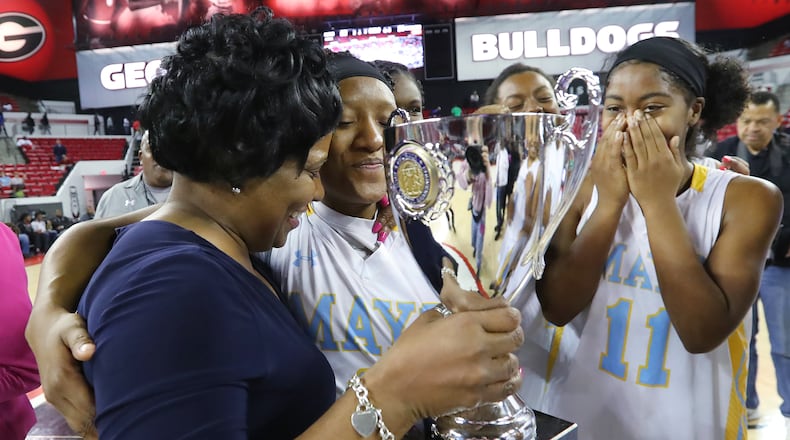 Mays point guard Kamiyah Street gives coach Chantay Frost a hug while handing her the trophy with Sierra Loving (right) looking on after defeating Harrison 52-51 in their Class AAAAAA girls state basketball championship game Thursday, March 9, 2017, in Athens. Curtis Compton/ccompton@ajc.com